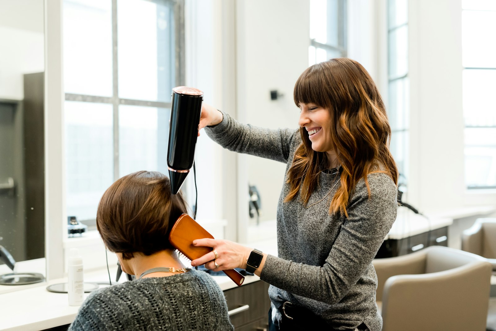 Stylist blow-drying a client's hair in a modern salon